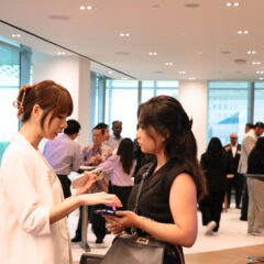 Chloe Koo, speaking with an attendee while guests enjoy refreshments at the back