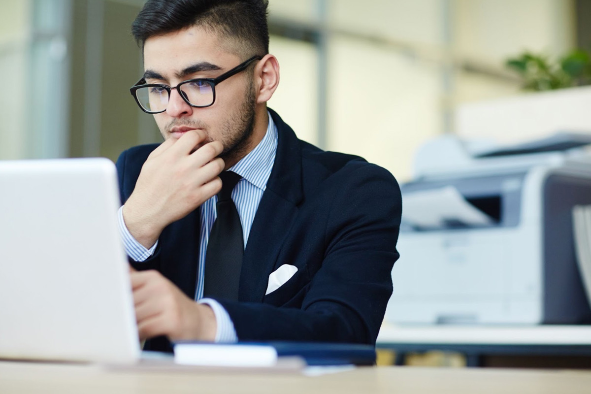 Guide to Deregister for GST in Singapore A business professional reviewing an official document on his laptop titled GST Deregistration Guide with a modern office setting in the background, symbolising the process to deregister for GST.